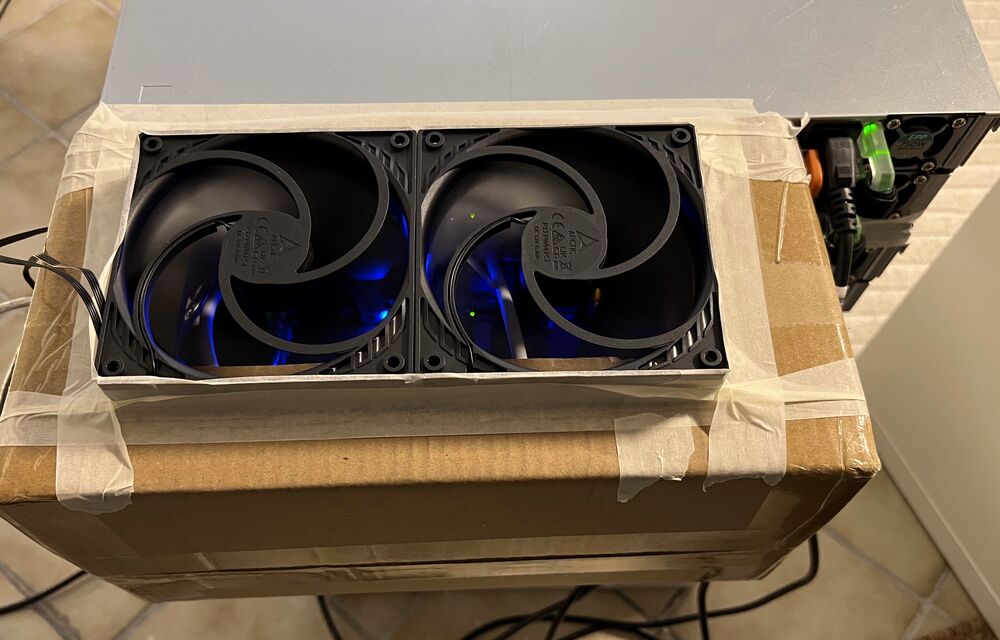 Two fans mounted in a cardboard box on a server