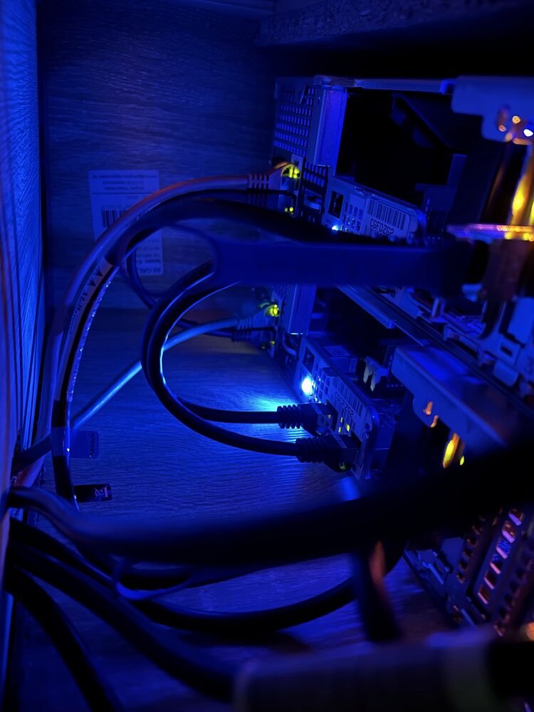 Rear of the two servers in blue light, with InfiniBand and Ethernet cables
